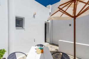 een witte patio met een tafel en een parasol bij Island Dreams in Adamas