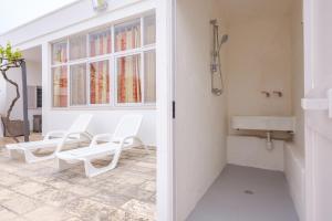 uma casa de banho com 2 cadeiras brancas e um lavatório. em Villa Stellina and Trullo Cecé em Ostuni