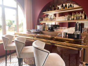 - un bar avec des chaises blanches et un comptoir avec des bouteilles de vin dans l'établissement Park Hotel Bellevue, à Trégastel