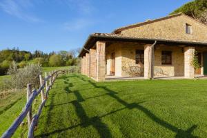 蒙特普齐亚诺Agriturismo Il Serraglio的一座古老的石头房子,在田野上设有围栏