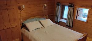 a bedroom with a bed and two windows at Les cabanes de pellier in Charcier