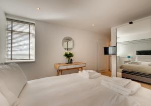 a white bedroom with a bed and a mirror at 3 Little Beach in Woolacombe