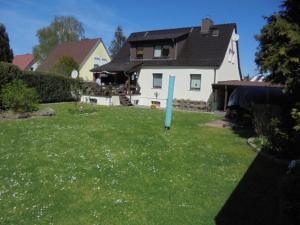 a house with a yard with a blue post in the grass at Ferienwohung am Stadtrand von Rostock in Rostock