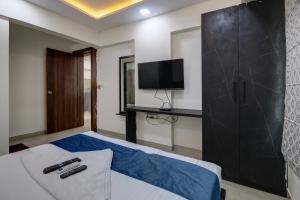 StayBird - Silver Oak, An Apartment Hotel, Kharadi في بيون: غرفة نوم بسرير وتلفزيون على جدار