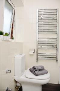a bathroom with a toilet with a towel on it at 29EW Dreams Unlimited Serviced Accommodation- Staines - Heathrow in Stanwell