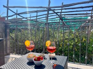a table with two glasses of wine and a bowl of fruit at Giardino di Nonno Lucio - Surrounded by Lemon Tree in Piano di Sorrento