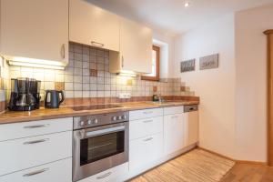 a kitchen with white cabinets and a stove top oven at Apartments Foidl in Kitzbühel