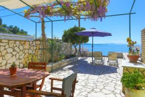 a patio with a table and an umbrella and the ocean at Kaminaki Beachfront Apartments in Nisaki