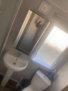 a bathroom with a sink and a toilet and a window at Community Wishes Retreat - Butlins Passes Included in Lincolnshire