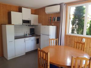 Fonyód Camping & Apartman في فونيود: مطبخ بأدوات بيضاء وطاولة خشبية