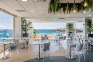 ein Restaurant mit Tischen und Stühlen und Meerblick in der Unterkunft Hotel Spa Porta Maris by Melia in Alicante