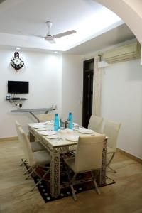 新德里的住宿－DIVINE INDIA SERVICE APARTMENT 3BHK, J-215 SAKET，餐桌、白色椅子和电视