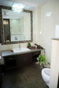 a bathroom with a sink and a mirror and a toilet at DIVINE INDIA SERVICE APARTMENT 3BHK, J-215 SAKET in New Delhi