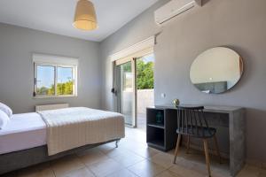 a bedroom with a bed and a mirror and a chair at Queen Electra with pool and tennis court in Alikianós