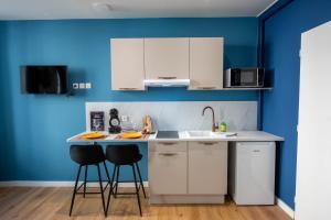a kitchen with white cabinets and blue walls at WelcomeAgen*Charlie Chaplin in Agen