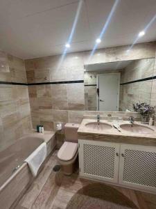 Un baño con dos lavabos, una bañera y un inodoro. en Sotogrande Marina Beach, en Sotogrande