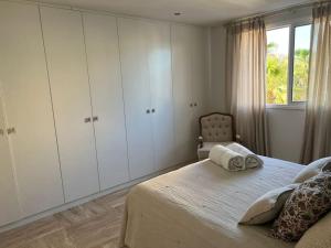 1 dormitorio con 1 cama con armarios blancos y ventana en Sotogrande Marina Beach, en Sotogrande