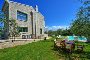 a house with a table and chairs in the yard at Villa Elaia by PosarelliVillas in Almiros Beach