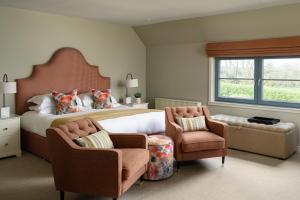 a bedroom with a large bed and two chairs at The Peat Inn Restaurant With Rooms in St. Andrews