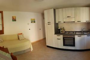 uma cozinha com armários brancos e um sofá num quarto em Casa Fiori em Pisciotta