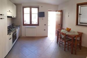 uma cozinha com uma mesa de madeira, uma mesa e cadeiras em Casa Fiori em Pisciotta
