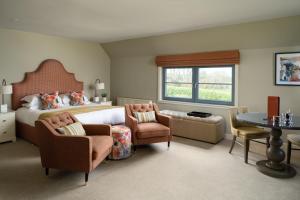 a bedroom with a bed and chairs and a table at The Peat Inn Restaurant With Rooms in St Andrews