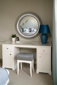 a dressing table with a mirror and a lamp and a stool at The Peat Inn Restaurant With Rooms in St. Andrews