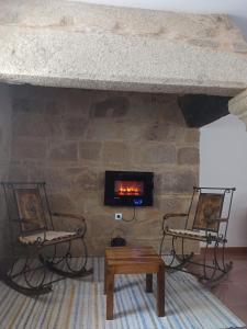 a living room with two chairs and a stone fireplace at A casa do campo in Zas