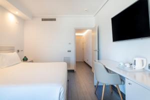 a room with a bed and a desk and a tv at INNSiDE by Meliá Alicante Porta Maris in Alicante
