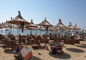 a group of people sitting on a beach with umbrellas at Seashell Beach Rooms in Durrës