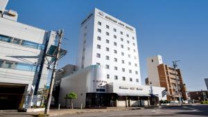 un edificio blanco alto en una calle de la ciudad en 小牧シティホテル, en Komaki