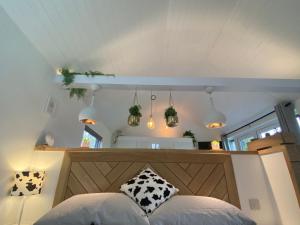 a bedroom with a bed with a wooden headboard and pendant lights at The Little Barn in Hoxne +108 photos