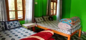 a green room with two twin beds in it at Blessing Homestay Ahaldara in Mangpu