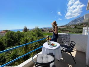 Una mujer en un balcón mirando el océano. en Odysseas Apartments, en Marathokampos