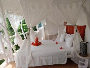 um quarto com uma cama branca com cortinas brancas em AL FARO Cosmio Hotel Palawan em Busuanga