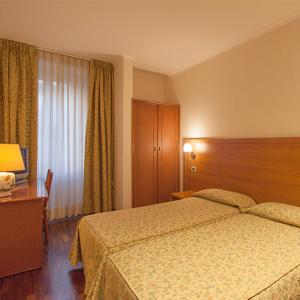 Habitación de hotel con cama, escritorio y ventana en Albergo Trattoria Friulana AL TAJ, en Sevegliano