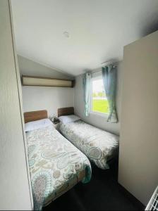 a small bedroom with two beds and a window at Community Wishes Retreat - Butlins Passes Included in Lincolnshire