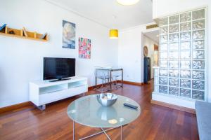 sala de estar con mesa de cristal y TV en Castilla Luz Deco, en Madrid