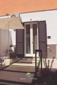 Casa con patio con sombrilla y mesa en Mare & Relax delux, en Margherita di Savoia