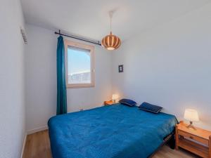 a bedroom with a blue bed and a window at Apartment Front de Mer-8 by Interhome in Le Barcarès
