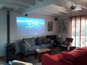 a living room with a couch and a projection screen at Maison en bois avec piscine à 1000 m des plages. in Guidel