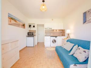 a living room with a blue couch and a kitchen at Apartment Les Jardins de la Nartelle Beach by Interhome in Sainte-Maxime