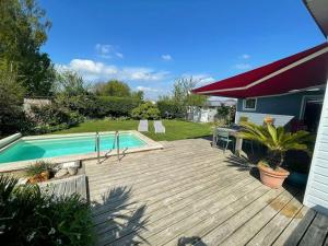a wooden deck with a swimming pool in a yard at Maison en bois avec piscine à 1000 m des plages. in Guidel