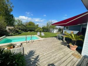 a wooden deck with a swimming pool in a yard at Maison en bois avec piscine à 1000 m des plages. in Guidel