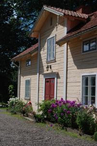 ein Holzhaus mit einer roten Tür und ein paar Blumen in der Unterkunft Kristbergs Rusthåll in Borensberg