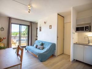 een woonkamer met een blauwe bank en een keuken bij Apartment Saint James-9 by Interhome in Le Lavandou