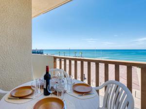 a table with a bottle of wine on a balcony with the beach at Apartment Ortal Océan-2 by Interhome in Lacanau-Océan