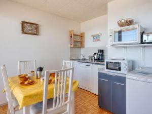 een keuken met een tafel en stoelen en een magnetron bij Apartment Ortal Océan-2 by Interhome in Lacanau-Océan