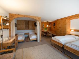 1 Schlafzimmer mit 2 Betten, einem Tisch und einem Schreibtisch in der Unterkunft Apartment Guardaval - Utoring-33 by Interhome in Davos