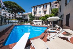 einen Pool mit Stühlen und Sonnenschirmen neben einem Gebäude in der Unterkunft Coccodrillo Hotel & Apartments in Varraze
